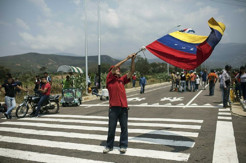 A supporter of the Venezuelan government waves a national flag Friday as people begin arriving for the three-day Hands Off Venezuela music festival at the Tienditas International Bridge on the border with Colombia. 