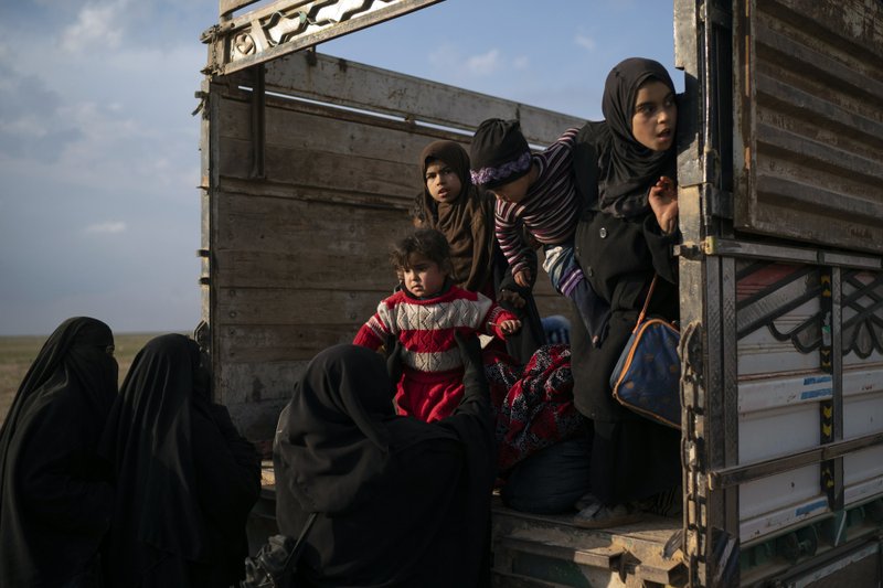 Women and children exit the back of a truck, part of a convoy evacuating hundreds out of the last territory held by Islamic State militants in Baghouz, eastern Syria, Friday, Feb. 22, 2019. (AP Photo/Felipe Dana)