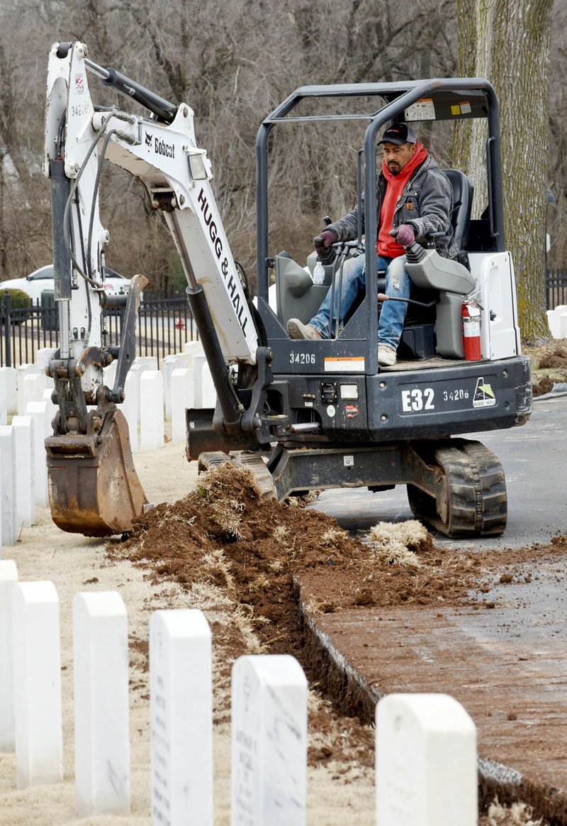 NWA Democrat-Gazette/DAVID GOTTSCHALK Mario Rodriguez, with Pavecon, drives a mini excavator Thursday to clear an area for new curbs at the Fayetteville National Cemetery. The work is part of planned improvements to the cemetery that includes parking lot expansion and the replacement of the curb. Curb work should finish by the end of the month, with the parking expansion taking place that.