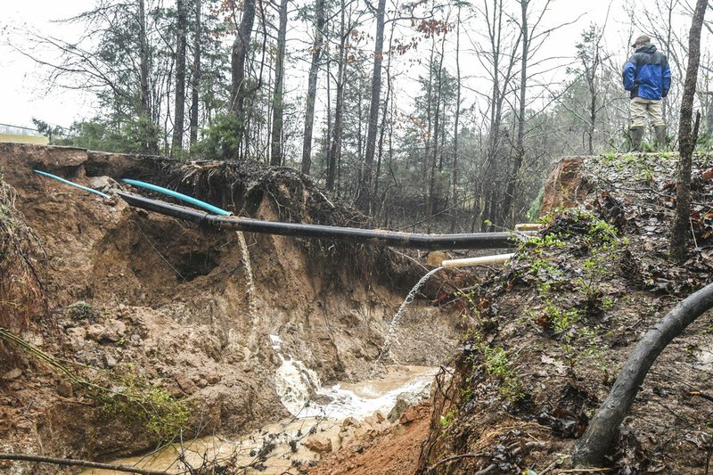 Hunter Maples looks over a water line break caused by heavy rainfall near the Max Hipp Industrial Park in Oxford, Miss. on Saturday, Feb. 23, 2019. The city of Oxford has issued a self-imposed precautionary boil-water notice for all customers that receive water from the city of Oxford, including those customers outside the city limits. (Bruce Newman/The Oxford Eagle via AP)