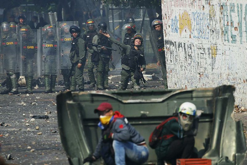 Demonstrators take cover as a Venezuelan National Guardsman hurls a tear gas grenade during clashes Saturday in Urena, Venezuela, near the Colombian border. 