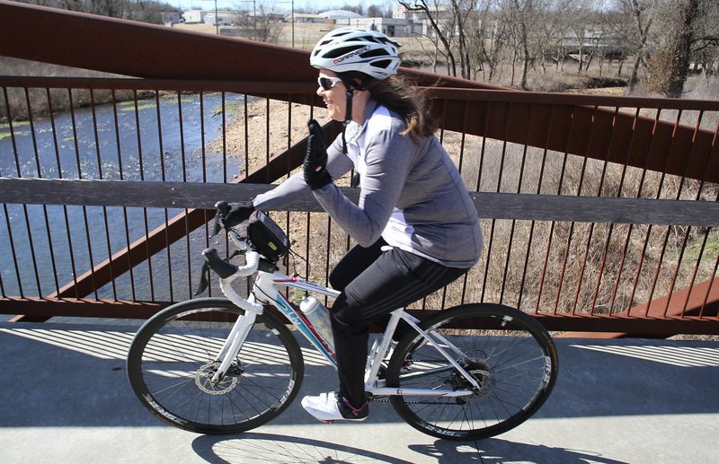 NWA Democrat-Gazette/DAVID GOTTSCHALK Melissa Peck passes a pedestrian Feb. 13 as she rides over the bridge on the Spring Creek Trail near the Lake Springdale Trailhead in Springdale. Springdale is contracting for an engineer to design an extension of Spring Creek Trail. The update runs from Lake Springdale trail head to the planned AG&amp;F education center on 40th Street.