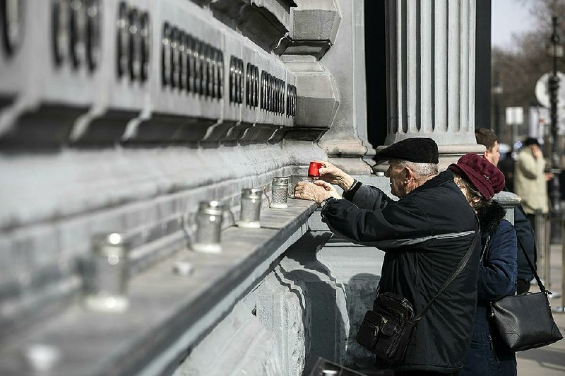 Elderly people light candles Monday at the Wall of Heroes outside the House of Terror Museum to pay tribute on Memorial Day of Victims of Communism in Budapest, Hungary.