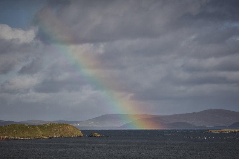 A rainbow cuts across the sky over the Shetland Islands off the coast of mainland Scotland. The rugged, isolated, moody nature of the islands creates a unique atmosphere for tourists.