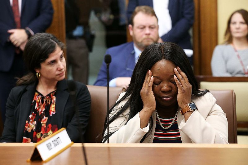 Committee member Jamie Scott (right), D-North Little Rock, tries to hold back her emotions during House committee debate on a bill that would change the meaning of the star above the word “Arkansas” on the state flag. For more photos see arkansasonline.com/227GenAssembly/. 