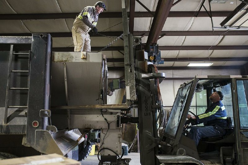 Rick Mosman (left) and Derek Henson install a salt bed on a Benton County Road Department truck Friday in Bentonville as they prepare for ice and snow expected to move in late Saturday and into today 