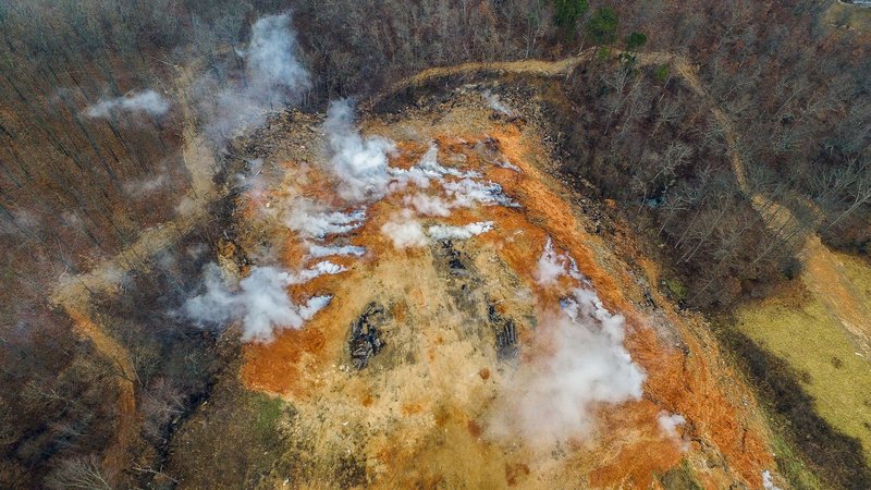 This March 1, 2019 photo provided by Apex Visual Solutions shows an underground fire at an illegal dumping site in Bella Vista, Ark. The fire, which started in July, is beneath dozens of feet of waste and dirt in a former dump intended for tree limbs and stumps. It has been smoldering for at least seven months, sending noxious smoke throughout the community, with costs to extinguish it estimated in the tens of millions. (C. Nelson/Apex Visual Solutions via AP)