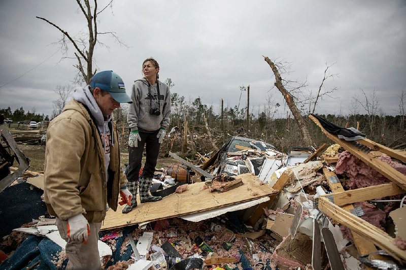 Ashley Griggs (right) helps Joey Roush sift through what’s left of his mother’s home Monday after it was destroyed by a tornado in Beauregard, Ala.