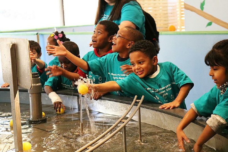 A visiting preschool group has splashy, wet fun with the Mid-America Science Museum’s fountain. 
