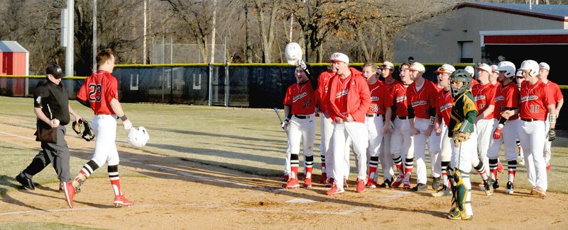 MARK HUMPHREY ENTERPRISE-LEADER/Farmington junior Drew Sturgeon receives congratulations from his teammates after belting a leadoff solo home run to ignite a 6-run first inning in the Cardinals' 12-7 victory over Alma on Tuesday, Feb. 26.