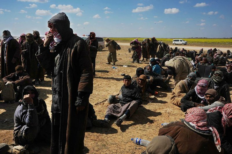Men wait for interrogation and security screenings Wednesday near Baghouz, Syria, after being moved out of Islamic State-held territory. The fighters left behind are willing to die, said a member of the group’s religious police who was evacuated. 