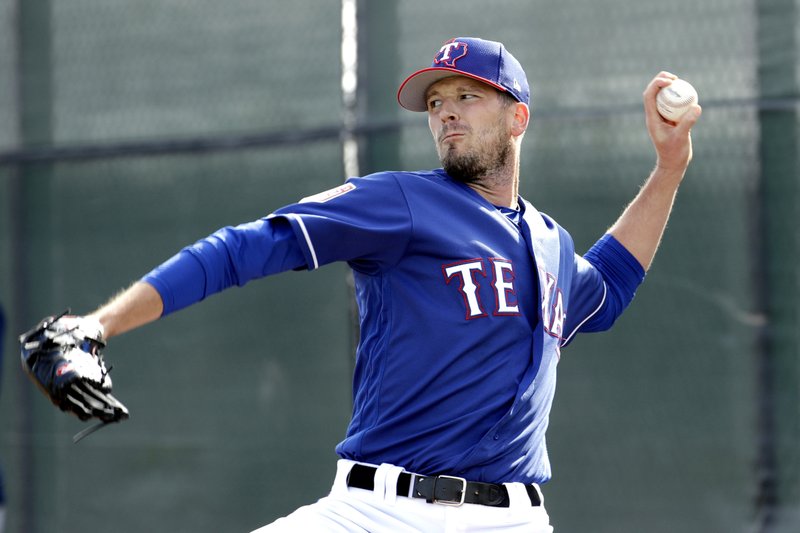  In this Feb. 15, 2019, file photo, Texas Rangers pitcher Drew Smyly throws during spring training baseball practice, in Surprise, Ariz. Smyly has been a member of three different organizations since his last major league pitch in 2016 with Tampa Bay. He was traded to Seattle in Jan. 2017, but got hurt in spring training. After the Mariners declined to offer him a contract, he signed a $10 million, two-year contract with the Cubs. The 29-year-old Smyly had Tommy John surgery on July 6, 2017. The left-hander struck out the side in a rehab appearance in August, but the contending Cubs ran out of time to get him into a game. He was traded to Texas in November. (AP Photo/Charlie Riedel, File)