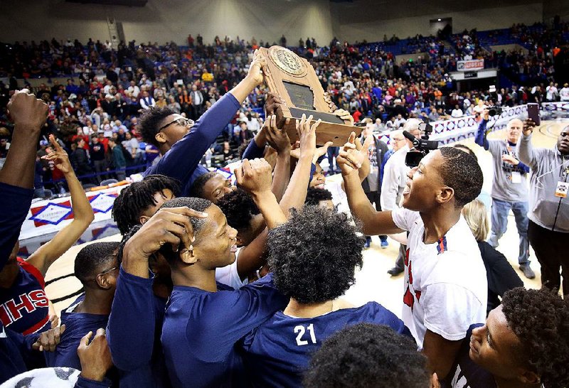 Marion players celebrate after the Patriots’ 57-54 overtime victory over Little Rock Hall in the Class 5A boys state basketball championship Thursday at Bank OZK Arena in Hot Springs.