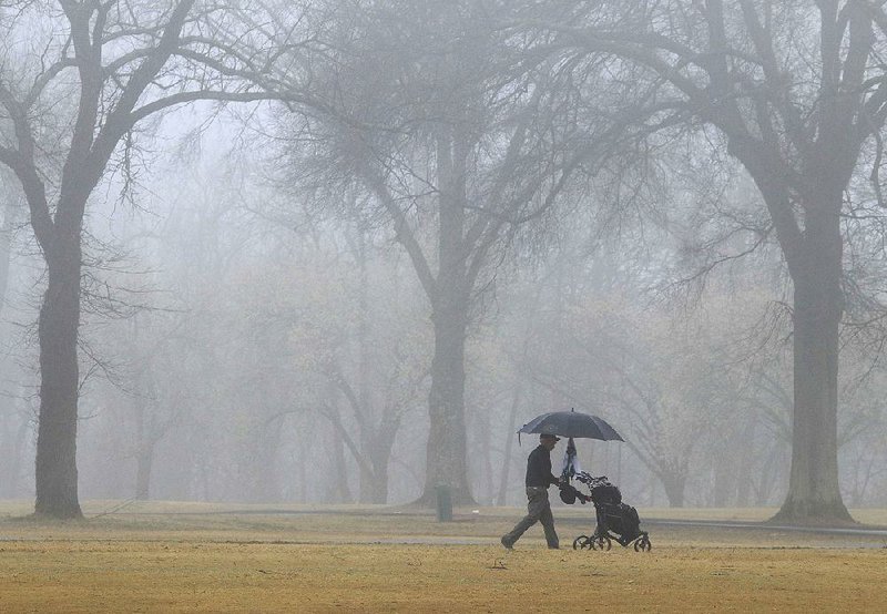 Arkansas Democrat-Gazette/STATON BREIDENTHAL --3/8/19-- Jack Bowell takes cover under his umbrella Friday as he plays a round of golf on a fog-covered course at Burns Park in North Little Rock. More photos online at arkansasonline.com/39fog/.