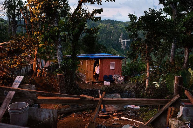 A man stands in the doorway of a home destroyed by Hurricane Maria. The storm also devastated the island’s economy. 