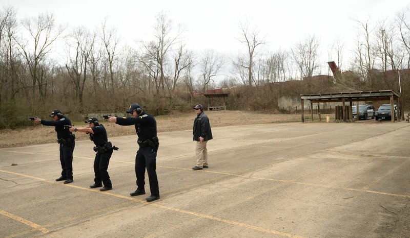 NWA Democrat-Gazette/ANDY SHUPE Instructor Terry Tate (right) gives commands Thursday as officers Andy Nunez (from left), Clarisa Navarro and Cpl. Aaron Tomlinson of the Fayetteville Police Department train at the department's gun range in south Fayetteville. About $35 million for a new police headquarters and $3 million in improvements to public buildings is included in a bond referendum Fayetteville voters will consider April 9.