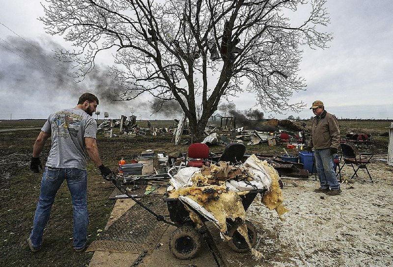 Josh Smith (left) hauls debris Sunday from the remnants of grandfather Doyne Carpenter’s antique store in Lonoke County just south of Carlisle. More photos are available at arkansasonline.com/311tornado/. 