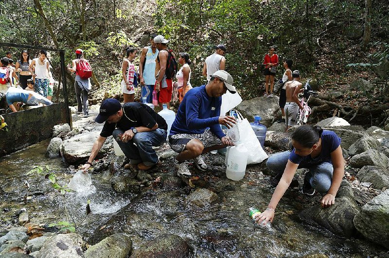 People in Caracas, Venezuela, collect water Sunday from a stream in Avila National Park after rolling blackouts cut off running water to homes and apartment buildings.