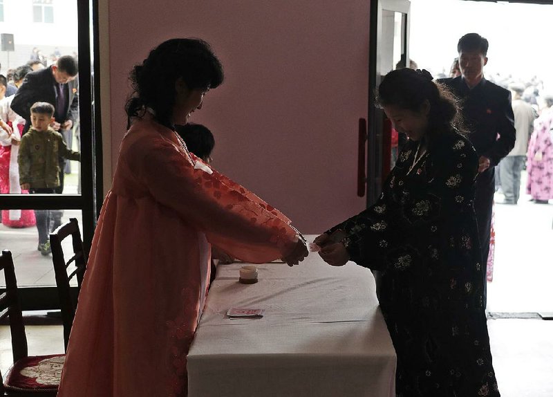A woman receives a ballot from an electoral worker Sunday at a polling station in Pyongyang, North Korea.