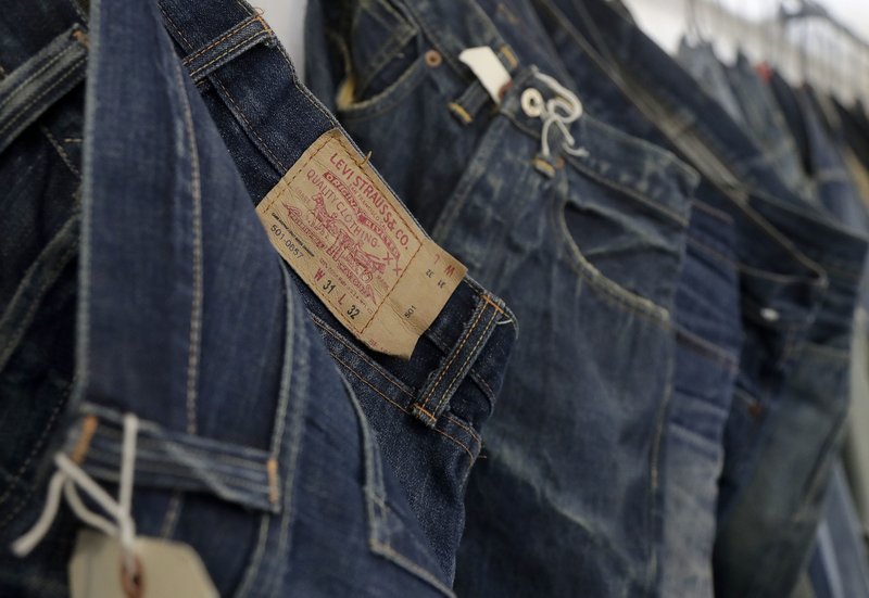 FILE - In this Feb. 9, 2018 photo Levi's jeans hang on a wall at Levi's innovation lab in San Francisco. Well-known jeans company Levi Strauss says it plans to raise up to $587 million through an initial public offering. The San Francisco-based company said Monday, March 11, 2019, that it&#x2019;s offering approximately 9.5 million shares, while selling stockholders are offering about 27.2 million shares. (AP Photo/Jeff Chiu, File)