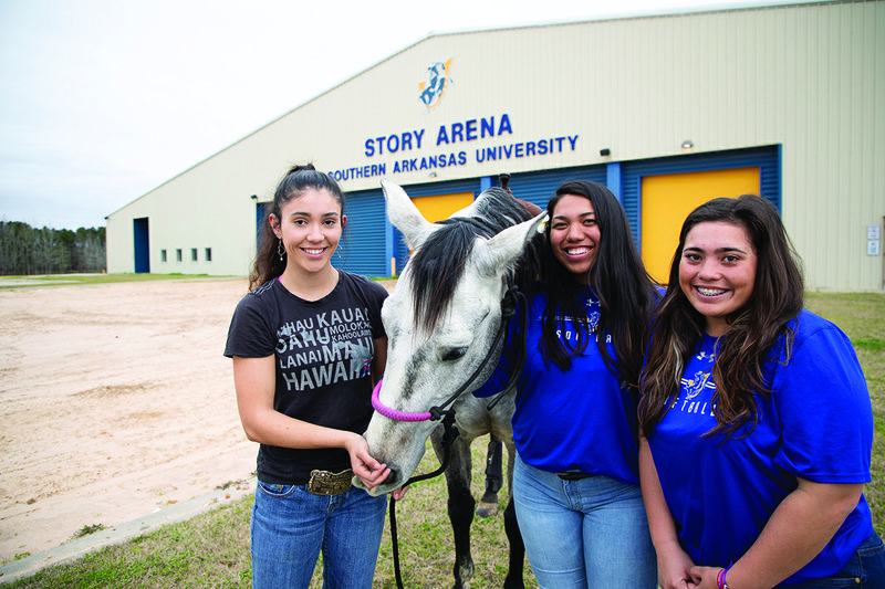 The three new Hawaiian Mulerider friends take Bobo for a walk at Story Arena. Pictured, from left, are Gabrielle Gleason, a junior Elementary Education major from Hilo, Hawaii; Ryah Kaniho, a junior Elementary Education major from Maui, Hawaii; and Elisa Favela, a sophomore pre-nursing major from Ouahu, Hawaii.