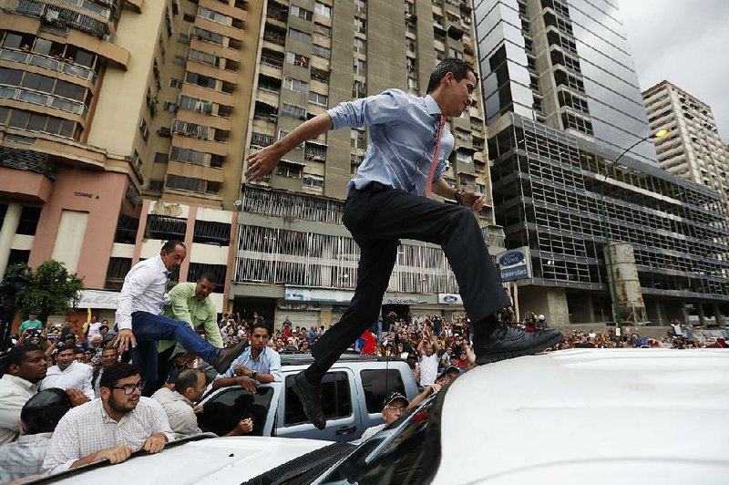 Venezuelan opposition leader Juan Guaido leaps onto a vehicle Tuesday in Caracas to address supporters, one of several appearances he made at protests around the Venezuelan capital. 