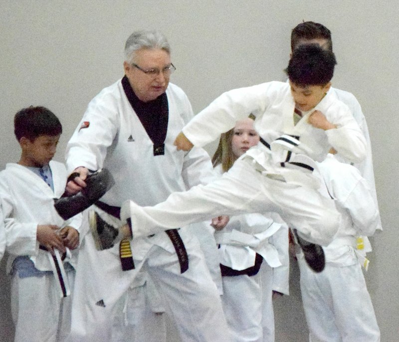 Westside Eagle Observer/MIKE ECKELS Dargin Herrera (right) demonstrates a flying kick during a TaeKwonDo exhibition at Northside Elementary in Decatur Feb. 21. Herrera and others in his class were part of the Spark after-school program at Northside.