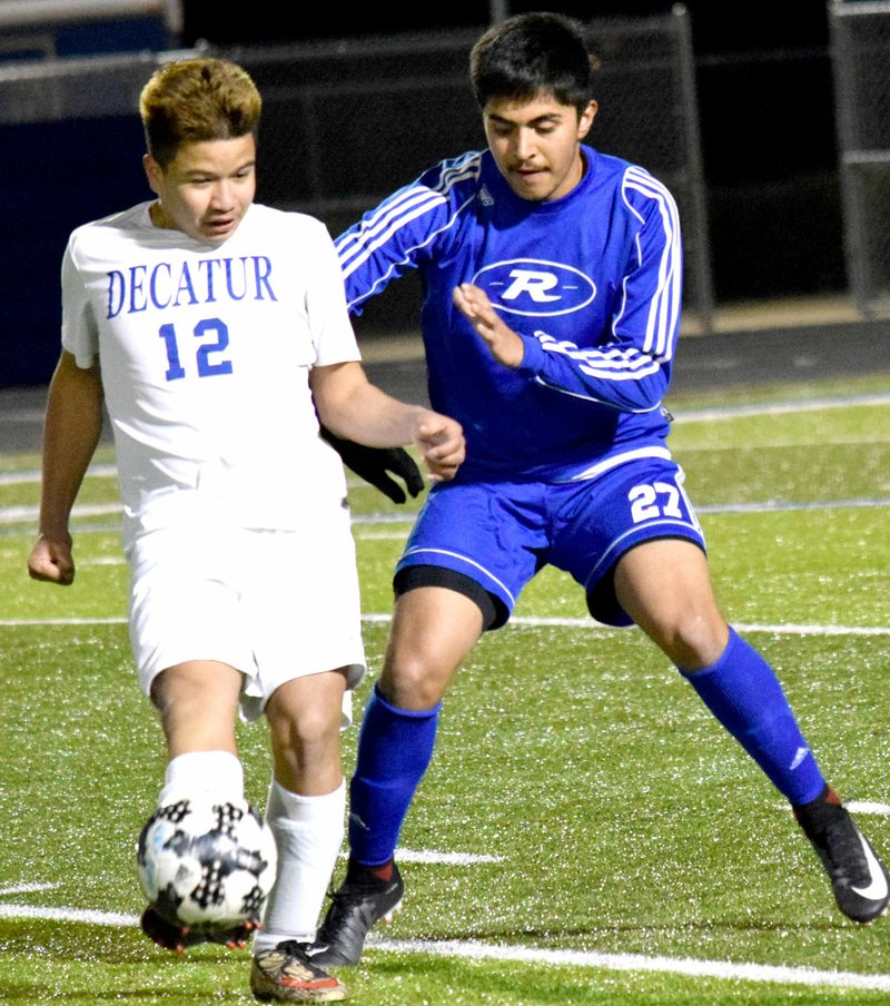 Westside Eagle Observer/MIKE ECKELS Kevin Sanchez (12) kicks the ball away from a Mounties player during the second half of the Rogers JV-Decatur soccer contest at Mountaineer Stadium in Rogers March 6.