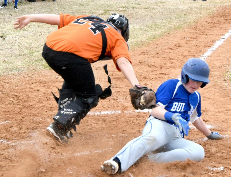 Westside Eagle Observer/MIKE ECKELS Bulldogs' Austin Hamilton crosses home plate just as the Engineer catcher makes a tag during the Decatur-Watts (Okla.) baseball contest at Edmiston Park in Decatur March 8. The home plate umpire ruled Hamilton safe, giving the Bulldogs another run.