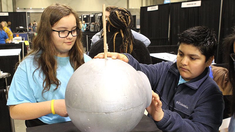 The Sentinel-Record/Richard Rasmussen DISPLAY TIME: Hot Springs Intermediate School students Candence Bishop, left, and Victor Grana work on setting up the school's booth at the 2019 EAST Conference at the Hot Springs Convention Center Tuesday.