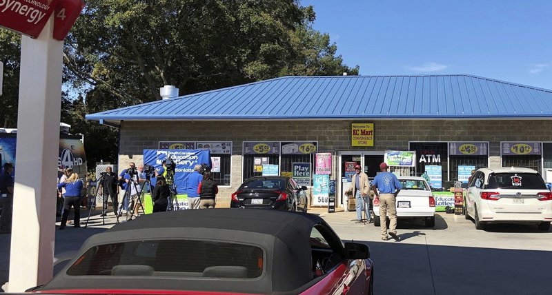 FILE - In this Oct. 24, 2018, file photo, media, at left, record people entering the KC Mart in Simpsonville, S.C., after it was announced the winning Mega Millions lottery ticket was purchased at the store.  (AP Photo/Jeffrey Collins, File)

