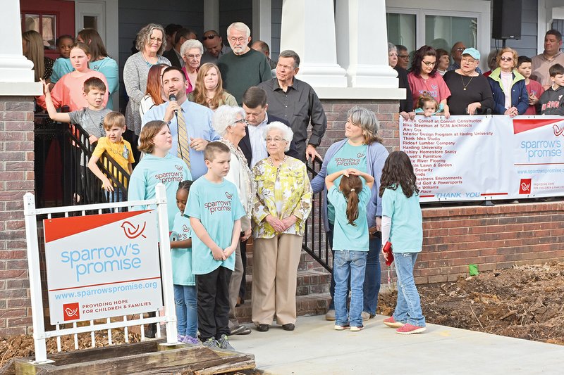 Brandon Tittle, center, with microphone, addresses the crowd gathered at the ribbon-cutting for Sparrow’s Promise, formerly Searcy Children’s Homes. The house on Moore Street, previously used as a group home and day care for foster children, was renovated with areas for foster children to temporarily wait when taken from their homes, as well as to meet with their biological parents. The house has classroom space and offices as well.