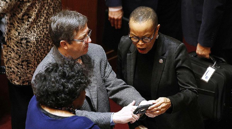 Sen. Joyce Elliott (right) and Sen. Linda Chesterfield, both Democrats from Little Rock, look at photos on the phone of Sen. Larry Teague, D-Nashville, in this photo.
