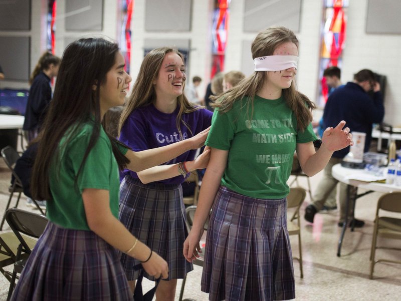 NWA Democrat-Gazette/CHARLIE KAIJO Stefany Mendoza, 13, Aubrey Holloway, 14 and Abigail Perry 13 (from left) play a blindfold game Thursday during a Pi Day celebration at St. Vincent de Paul Catholic School in Rogers. Students celebrated with a pie eating contest, games and a pinata. Pi Day is an annual celebration of the mathematical constant pi. The day is observed March 14 "since 3, 1 and 4 are the first three digits of pi, giving the kids an opportunity to get out of the classroom, do something fun and incorporate math," said Amy Liddell, seventh- and eighth-grade math teacher.