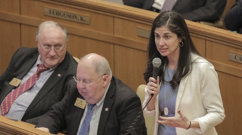 Rep. Nicole Clowney (right) , D-Fayetteville, is shown asking questions during a House session at the capitol in Little Rock. Representatives, from left,  Bruce Coleman and Steve Hollowell, listen in.