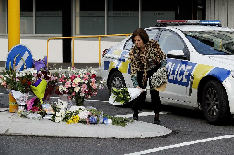 A woman in Christchurch, New Zealand, places flowers Friday at a makeshift memorial near a mosque where a mass shooting occurred Thursday. At least 49 people were killed in assaults on two mosques in Christchurch. 