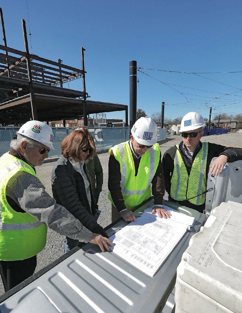 A group of officials — (from left) Jimmy Alessi, chief executive officer of Alessi Keyes Construction; North Little Rock council member Debi Ross; Bob Butler, president of Alessi Keyes Construction; and Nathan Hamilton with North Little Rock’s communications department — look at plans for the Argenta Plaza complex in downtown North Little Rock on Friday morning. 