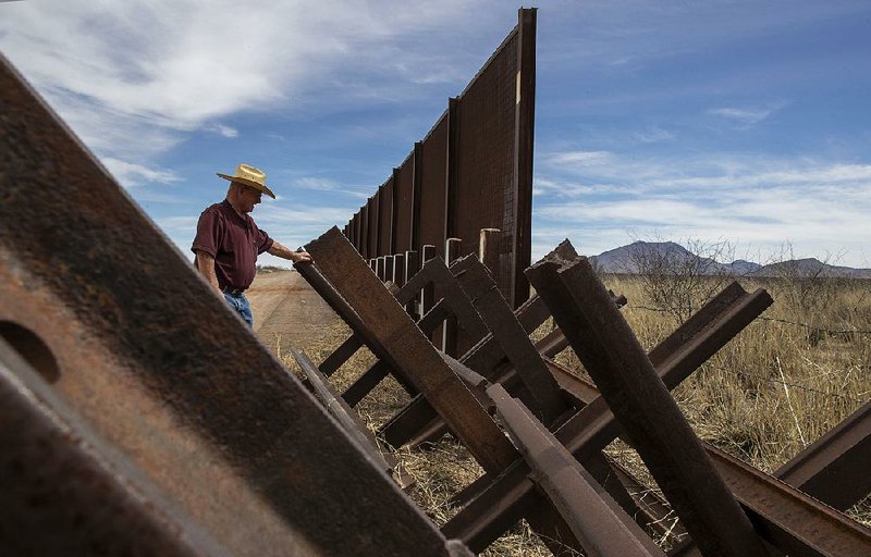 Gary Thrasher looks over a Normandy vehicle barrier near the San Pedro River bordering his friend and fellow rancher John Ladd’s property in Cochise County, Ariz., earlier this month. 