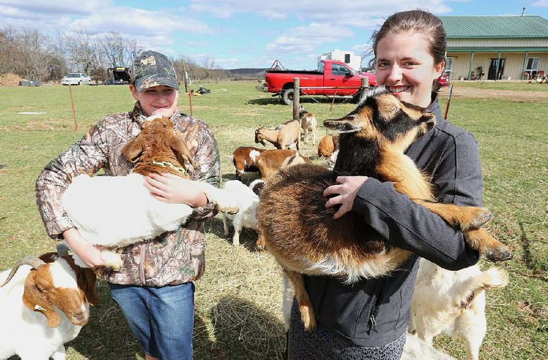 Sicily Burnett (left) and her sister Sierra hold goats Thursday on the family farm, D4S Farms, in Winslow. The Burnett family raises poultry, cattle, hogs, ducks and goats on a 500-acre farm. 