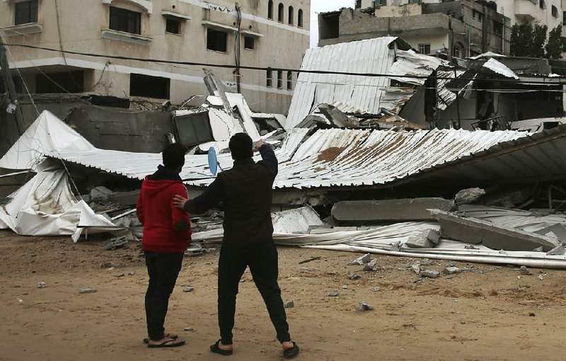 Palestinians inspect the damage of a destroyed building belonging to Hamas’ ministry of prisoners hit by Israeli airstrikes in Gaza City, early Friday. 