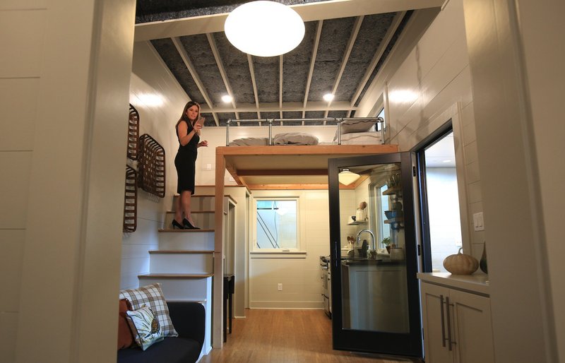 Beth Franks takes photographs September 6 of the tiny house her husband, Bret Franks of Bret Franks Construction Inc. built inside the Clinton Presidential Center for the "White House Green Building" exhibit. \. Arkansas Democrat-Gazette photo by Staton Briedenthal