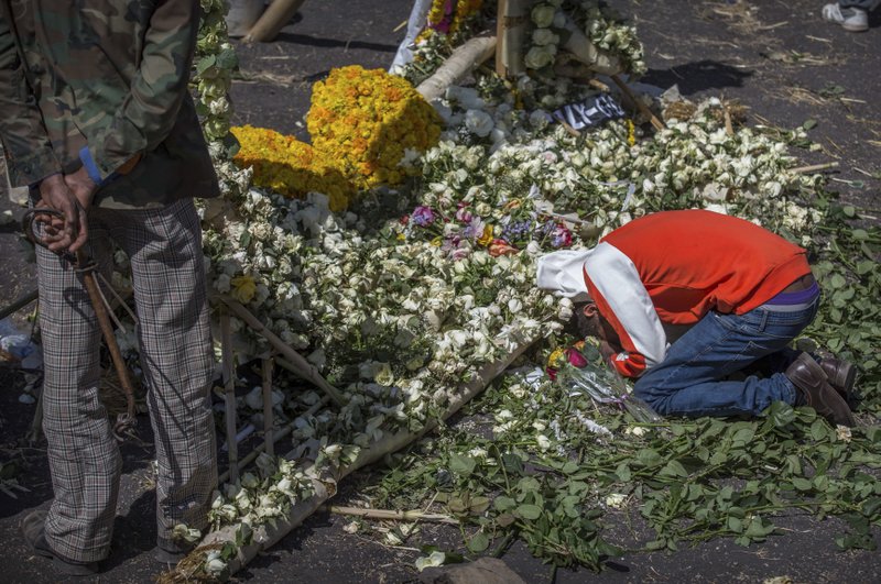 An Ethiopian relative of a crash victim mourns and grieves next to a floral tribute at the scene where the Ethiopian Airlines Boeing 737 Max 8 crashed shortly after takeoff on Sunday killing all 157 on board, near Bishoftu, south-east of Addis Ababa, in Ethiopia Friday, March 15, 2019. Analysis of the flight recorders has begun in France, the airline said Friday, while in Ethiopia officials started taking DNA samples from victims' family members to assist in identifying remains. (AP Photo/Mulugeta Ayene)