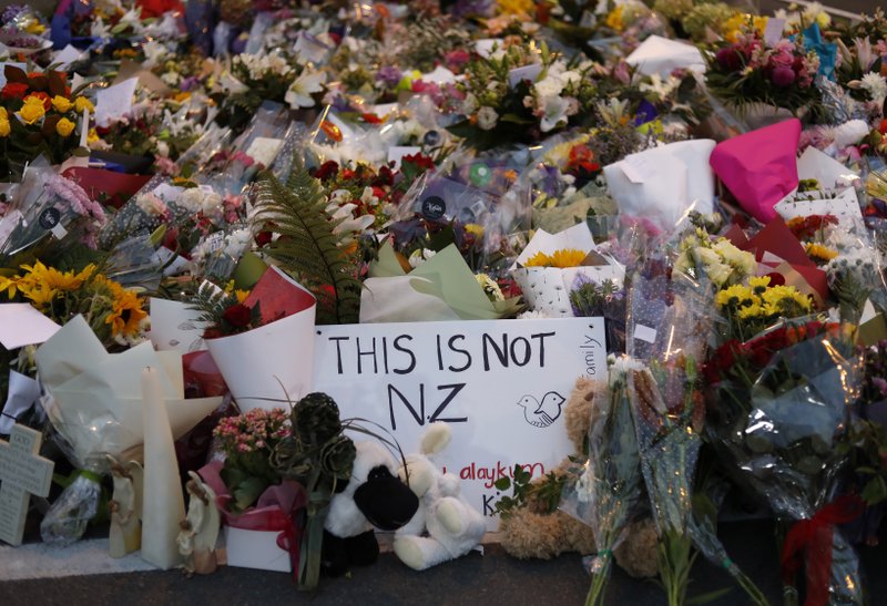 Mourners place flowers as they pay their respects at a makeshift memorial near the Masjid Al Noor mosque in Christchurch, New Zealand, Saturday. New Zealand's stricken residents reached out to Muslims in their neighborhoods and around the country on Saturday, in a fierce determination to show kindness to a community in pain as a 28-year-old white supremacist stood silently before a judge, accused in mass shootings at two mosques that left dozens of people dead. (AP Photo/Vincent Yu)

