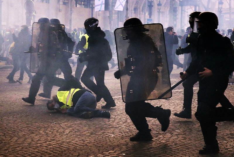 Riot police officers charge through the ranks of protesters Saturday in Paris. Police said 192 people were arrested and 60 injured, including 18 firefighters and policemen. 