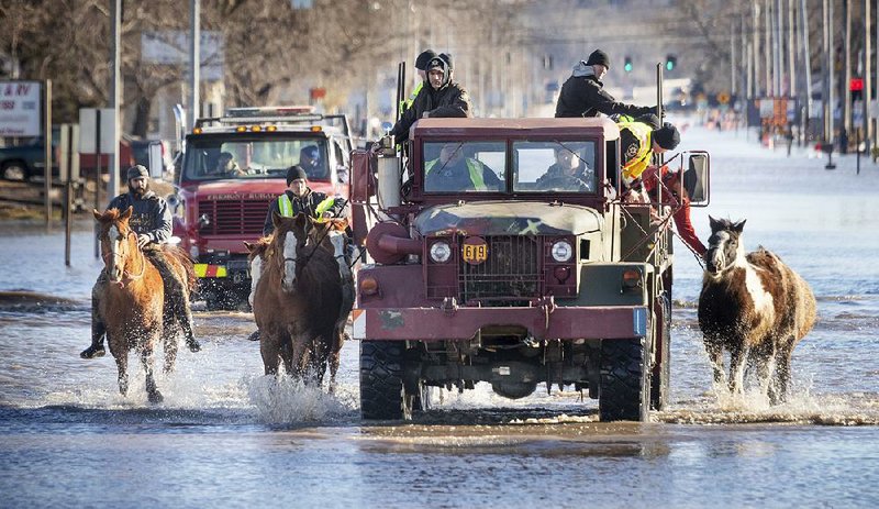 People guide horses through a flooded street in Fremont, Neb., on Friday. 