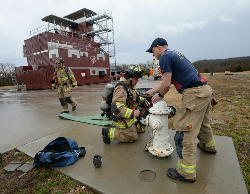 NWA Democrat-Gazette/ANDY SHUPE Marcus Mason (right) and Nathan Whitekiller, both Fayetteville firefighters, charge a fire hose Wednesday during high rise firefighting training at the department's training facility in south Fayetteville. City voters will head to the polls April 9 to consider 10 bond questions totaling more than $226 million in projects. About $15 million is included for the Fire Department for three new fire stations, trucks and equipment.
