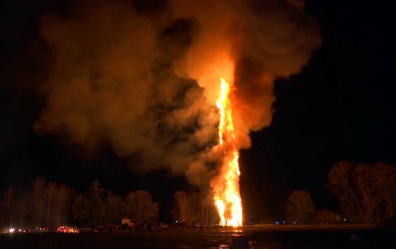 In this image made from video on Saturday, March 16, 2019, a bonfire burns in Lustenau, Austria. An Austrian town has burned what organizers says is the world's tallest bonfire, clocking in at 60.646 meters (198.97 feet). The local bonfire group in Lustenau, near the Swiss border, took three months to build the structure. The previous record structure was a 47-meter (154.2-foot) bonfire in Alesund, Norway in 2016. (AP Photo)