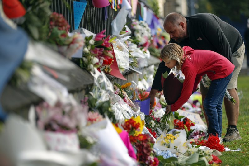 Mourners lay flowers on a wall at the Botanical Gardens in Christchurch, New Zealand, on Saturday. New Zealand's stricken residents reached out to Muslims in their neighborhoods and around the country on Saturday, in a fierce determination to show kindness to a community in pain as a 28-year-old white supremacist stood silently before a judge, accused in mass shootings at two mosques that left dozens of people dead. (AP Photo/Vincent Thian)

