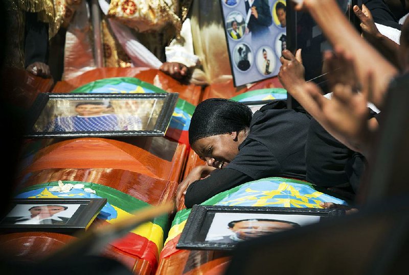 A woman grieves over empty caskets draped with Ethiopian flags Sunday at a mass funeral at the Holy Trinity Cathedral in Addis Ababa. Thousands of people attended the ceremony held in memory of the victims of last week’s Ethiopian Airlines crash. 