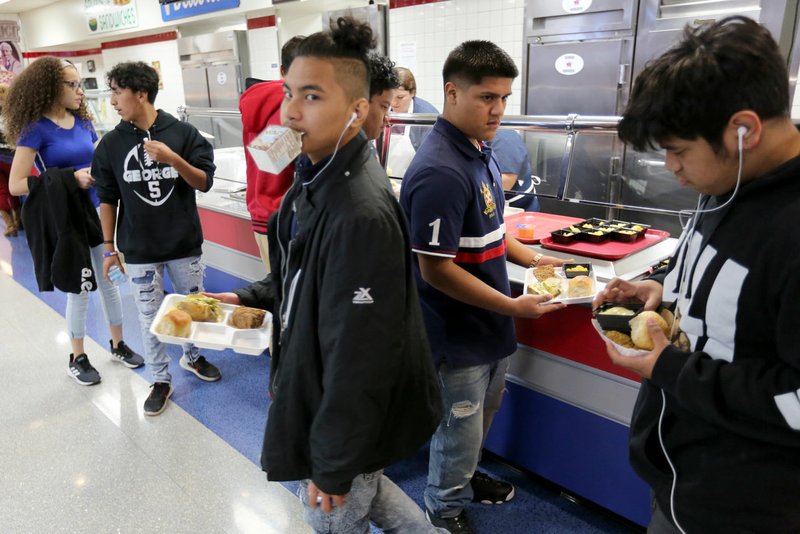 NWA Democrat-Gazette/DAVID GOTTSCHALK Johnny River, a freshman at George Junior High School, walks with his lunch Friday through the cafeteria at the Springdale school. University of Arkansas for Medical Sciences researchers are working with the Springdale School District to help reduce sodium in school lunches.